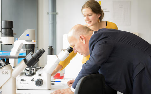 Der regierende Bürgermeisters Kai Wegner blickt in ein Mikroskop